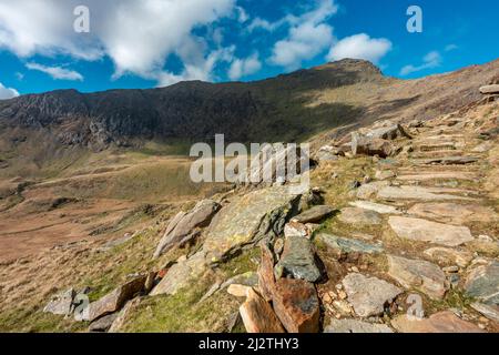 Eine lange und steile Route hinauf zum Gipfel des Mount Snowdon, an einem sonnigen Tag im März mit felsigen schmalen Wegen, lockeren Geröll und schöner Aussicht auf Snowdonia Stockfoto