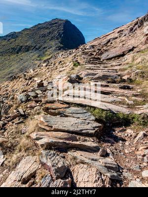 Eine lange und steile Route hinauf zum Gipfel des Mount Snowdon, an einem sonnigen Tag im März mit felsigen schmalen Wegen, lockeren Geröll und schöner Aussicht auf Snowdonia Stockfoto