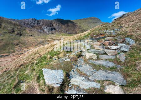 Eine lange und steile Route hinauf zum Gipfel des Mount Snowdon, an einem sonnigen Tag im März mit felsigen schmalen Wegen, lockeren Geröll und schöner Aussicht auf Snowdonia Stockfoto