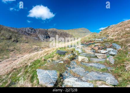 Eine lange und steile Route hinauf zum Gipfel des Mount Snowdon, an einem sonnigen Tag im März mit felsigen schmalen Wegen, lockeren Geröll und schöner Aussicht auf Snowdonia Stockfoto