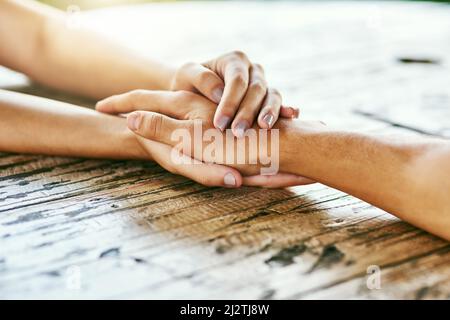 Sprecht mit mir und lasst mich Euch helfen. Nahaufnahme eines Mannes und einer Frau, die die Hände bequem auf einem Tisch halten. Stockfoto