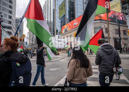 Toronto, Kanada. 02. April 2022. Während der Kundgebung schwenken die Demonstranten auf einem Fußgängerüberweg palästinensische Fahnen. Demonstranten versammelten sich auf dem Yonge-Dundas-Platz in Toronto, Kanada, in Solidarität mit Palästina. Kredit: SOPA Images Limited/Alamy Live Nachrichten Stockfoto