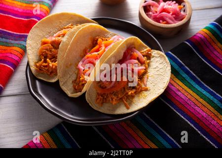 Tacos de Cochinita Pibil. Typisch mexikanischer Eintopf aus Yucatan, hergestellt aus Schweinefleisch, mariniert mit Achiote und in der Regel mit Bohnen und roten Zwiebeln begleitet Stockfoto