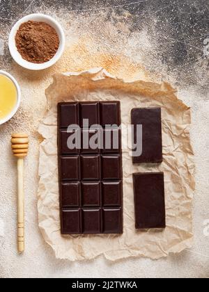 Gesunde, zuckerfreie, hausgemachte dunkle Schokolade mit Kakao und Honig auf Bastelpapier. Große und kleine Bars Stockfoto