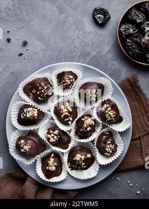 Gesund zuckerfrei hausgemacht Rohes veganes Schokoladen-Bonbons mit getrockneten Pflaumen und Nüssen auf blauem Hintergrund flach legen Stockfoto