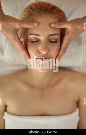 Sich in einem Tag voller Freizeit und Luxus verlaufen. Aufnahme einer jungen Frau, die in einem Spa eine Kopfmassage genießt. Stockfoto