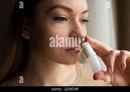 Das Mädchen verwendet Spray auf einem dunklen Hintergrund. Medizin und Behandlung Stockfoto