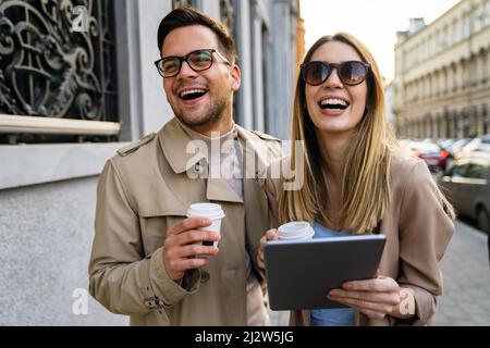 Portrait von glücklicher Frau und Mann, die mit Kaffee, digitalem Tablet und Spaß auf der Straße unterwegs sind. Stockfoto