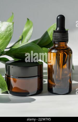 Set von Naturkosmetik für Gesicht und Körper. Pipettentropfer aus dunklem Glas ohne Marke und Cremeglas in gemütlicher Lifestyle-Atmosphäre. Natutal Öko-Trend. Stockfoto