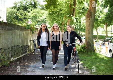 Nachholbedarf nach der Schule. Drei Freunde, die von der Schule nach Hause gehen. Stockfoto