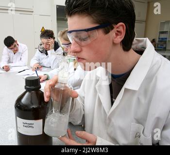 Niederlande, ein Student während eines Chemieunterrichts bläst in Kalkwasser, um das Kohlendioxid in der Luft zu zeigen, die er atmet. Stockfoto