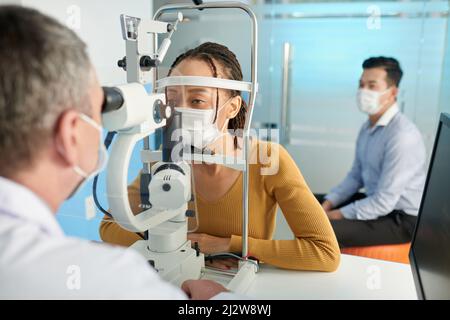 Junge Frau, die intraokularen Druck in der medizinischen Praxis der Optiker gemessen Stockfoto