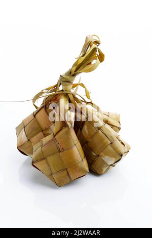 Ketupat Reisknödel Spezialgericht serviert im Eid Mubarak. Isoliert auf weißem Hintergrund. Ketupat ist gekochter Reis mit jungen Kokosnussblättern, die Eid al umhüllten Stockfoto