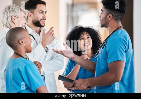 Die Köpfe, um jedes medizinische Geheimnis zu lösen. Aufnahme einer Gruppe junger Ärzte, die in einem modernen Büro ein Gespräch führen. Stockfoto