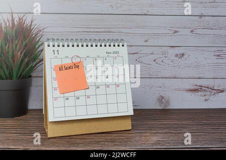 Kalender November 2022 auf Holztisch mit Datumskreis und Text auf Haftnotiz. Allerheiligen am 1.. November 2022. Stockfoto