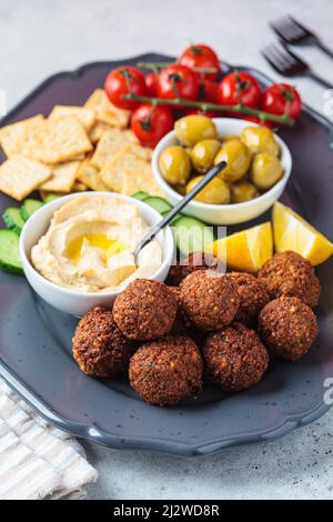 Falafel mit Hummus, Oliven, Crackern und Gemüse, Nahaufnahme. Gesundes veganes Lebensmittelkonzept. Stockfoto