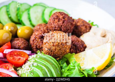 Falafel-Salatschüssel mit Hummus, Avocado, Oliven und Gemüse, Nahaufnahme. Gesundes veganes Lebensmittelkonzept. Stockfoto