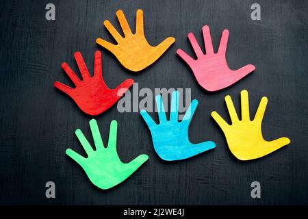 Farbige Handflächen auf dunklem Hintergrund. Diversity- und Inklusionskonzept. Stockfoto