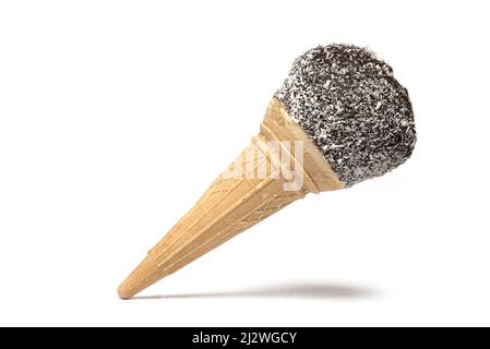 Nahaufnahme eines süßen Eiskonus-Bechers, gefüllt mit Zuckerschaum und bedeckt mit Schokolade und Kokosnussstreuseln auf weißem Hintergrund Stockfoto