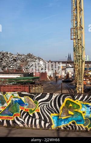 Schrottplatz mit altem Metall im Stadtteil Deutz, im Hintergrund der Dom, Wand mit Graffiti, Köln, Deutschland. Schrottplatz mit Altmetall im Stockfoto