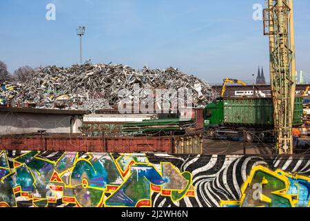 Schrottplatz mit altem Metall im Stadtteil Deutz, im Hintergrund der Dom, Wand mit Graffiti, Köln, Deutschland. Schrottplatz mit Altmetall im Stockfoto