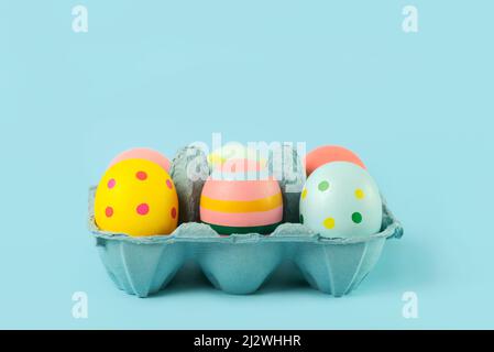 Frohe Ostern. Ostern bemalte Eier in einem offenen blauen Karton auf blauem Hintergrund Stockfoto