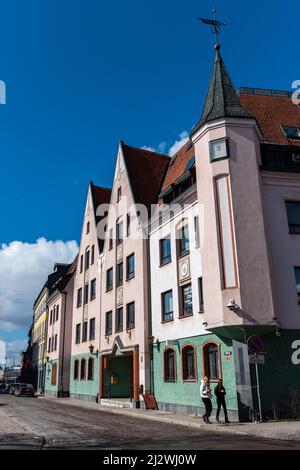 Eine Straßenecke in der Altstadt von Riga, Lettland mit einem historischen Gebäude und zwei Personen, die auf dem Bürgersteig spazieren gehen Stockfoto