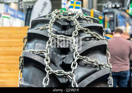 Nahaufnahme einiger Traktorräder mit Reifenkette. Brandneue Traktor- und Ladereifen. Stockfoto