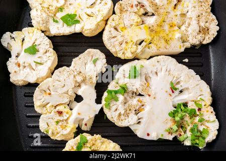 Kochen Blumenkohlsteak mit Kräutern und Gewürzen. Gesunder vegetarischer Snack, Nahaufnahme. Stockfoto