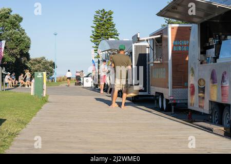 Tauranga Neuseeland - 3 2022. April; am Sommernachmittag findet die Marine Parade des Mount Maunganui statt, bei der Lebensmittel- und Getränkehersteller Lieferwagen und Menschen kaufen. Stockfoto