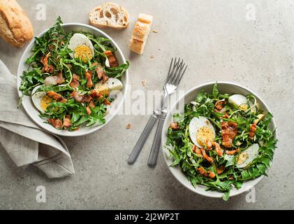 Dandelionensalat mit Eiern und Speck auf grauem Hintergrund Stockfoto
