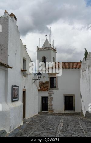 Monsaraz, Portugal - 23. März 2022: Idyllische Kopfsteinpflasterstraße im Zentrum des Dorfes Monsaraz mit malerischen weiß getünchten Häusern Stockfoto