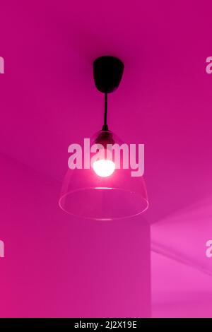 Lampe an der Decke im Zimmer in rosa Licht Stockfoto