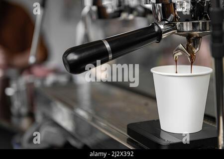 Eine Tasse Kaffee, der aus einer industriellen Kaffeemaschine zubereitet wird Stockfoto