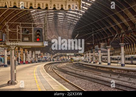 Bahnhof, wo a19. Jahrhundert Baldachin aus Eisen und Glas decken die Plattformen. Sonnenlicht ist auf der Plattform und ein Signallicht ist im Vordergrund. Stockfoto