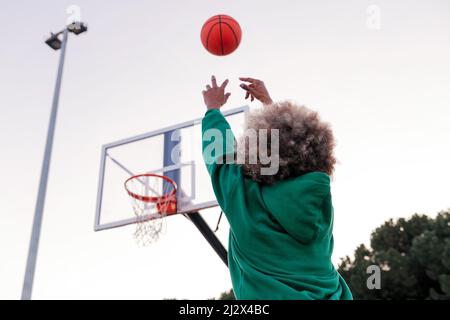 Unkenntliche Frau, die einen Ball in einen Basketballkorb wirft, Konzept des urbanen Sports auf der Straße, Platz für Text kopieren Stockfoto