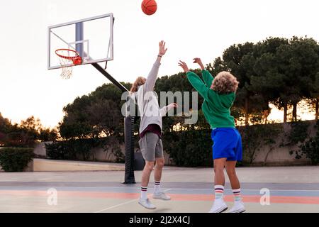 Zwei junge Freunde spielen Basketball auf einem Stadtplatz, Konzept des städtischen Sports auf der Straße, kopieren Raum für Text Stockfoto