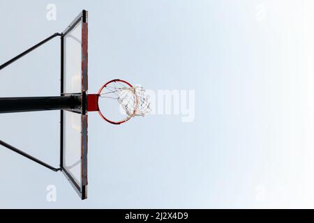 Horizontales Foto eines Basketballkorps von unten mit dem Himmel im Hintergrund, Konzept des urbanen Sports im Freien, Platz für Text kopieren Stockfoto
