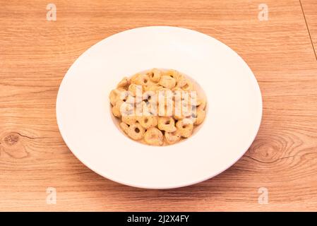 Platte mit köstlichen Tortellini in Tartufo-Sauce auf weißem Teller und hellem Holztisch mit Knoten Stockfoto