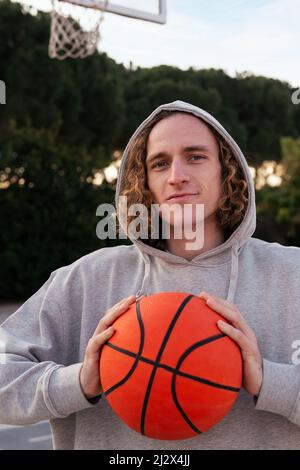 Junger Kaukasier, der einen Basketball in den Händen hält, Konzept des urbanen Sports im Freien, Platz für Text kopieren Stockfoto