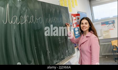 Hamburg, Deutschland. 04. April 2022. Tatjana Yahodka, die erste ukrainische Flüchtlingslehrerin an Hamburger Schulen, schreibt in einem Klassenzimmer des Louise-Weiss-Gymnasiums auf der Tafel "Willkommen" auf Ukrainisch. Quelle: Markus Scholz/dpa/Alamy Live News Stockfoto