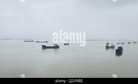 Ein schöner Blick auf Frachtschiffe im Meer mit leichtem Nebel gegen einen grauen Himmel am Horizont Stockfoto