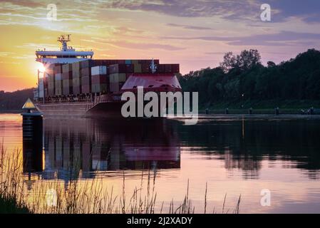 Ein Containerschiff auf der NOK in Richtung Kiel wurde bei Sonnenuntergang gefangen Stockfoto