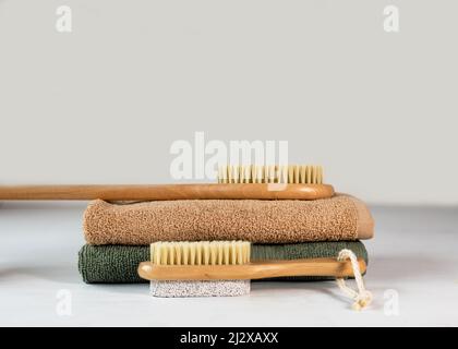Hausgemachte Bio-Seife auf Pflanzenbasis mit und einem Bambus-Massagebürste mit natürlichen Borsten auf einem grünen Frottee-Handtuch. Home SPA-Konzept, Selbstversorgung. Stockfoto