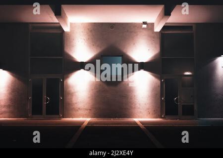 Gebäude beleuchtet mit Licht in der Nacht in einer Stadt, Nahaufnahme eines Gebäudes in der Nacht, zwei Türen, Eingang eines Gebäudes in der Nacht Stockfoto