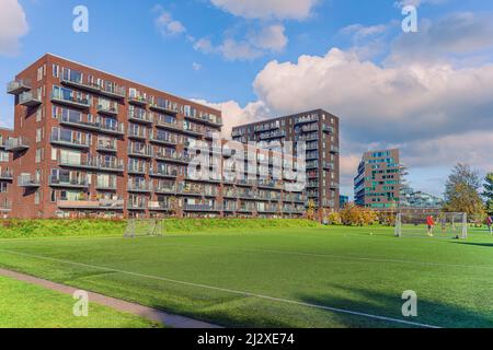 Modernes braunes Wohnapartmentgebäude in der Nähe des Byparken Parks und des Fußballplatzes in Ørestad. Kopenhagen, Dänemark Stockfoto