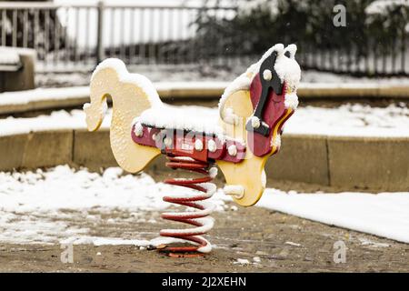 Schaukelnde Pferde zurück in Kinderspielplatz Park mit dicken Pack von Schnee bedeckt. Stockfoto