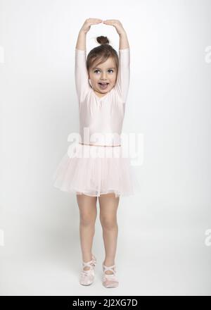 Kleine Ballerina in rosa Tutu mit Spaß üben ihre Bewegungen im Studio mit weißem Boden und Hintergrund Stockfoto