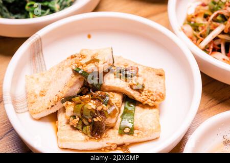 Würziger Kimchi. Koreanisches Gurkengemüse oder eingelegtes Rettichgemüse und Gewürze auf Schüssel auf Holztisch Hintergrund, japanisches Essen Stockfoto