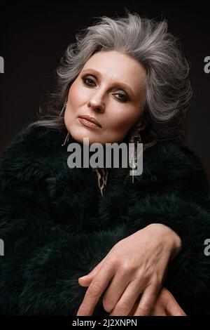Porträt einer schönen älteren Frau in Leopardenbluse und Pelzmantel mit klassischem Make-up und grauem Haar. Stockfoto